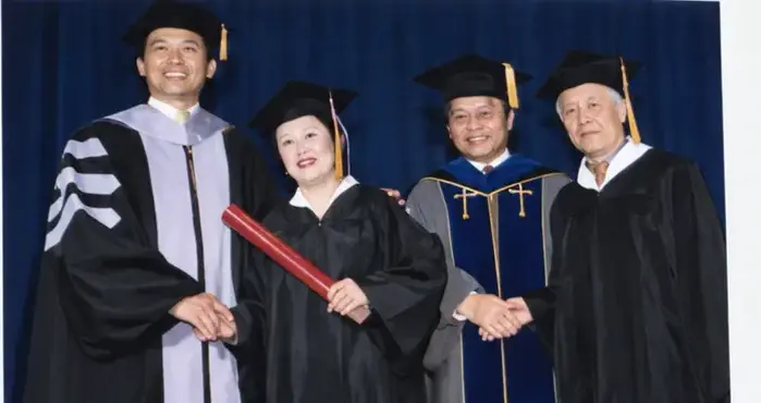 Graduate with College representatives at commencement